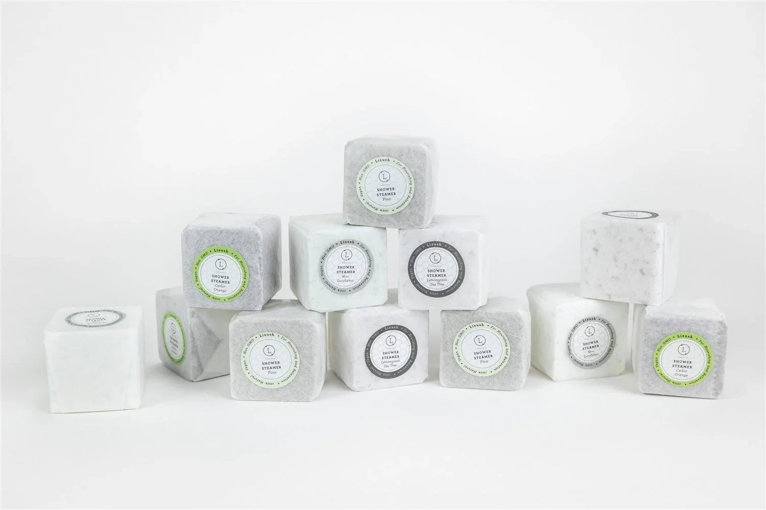 Stack of natural shower steamers in white and gray cubes with various scented labels