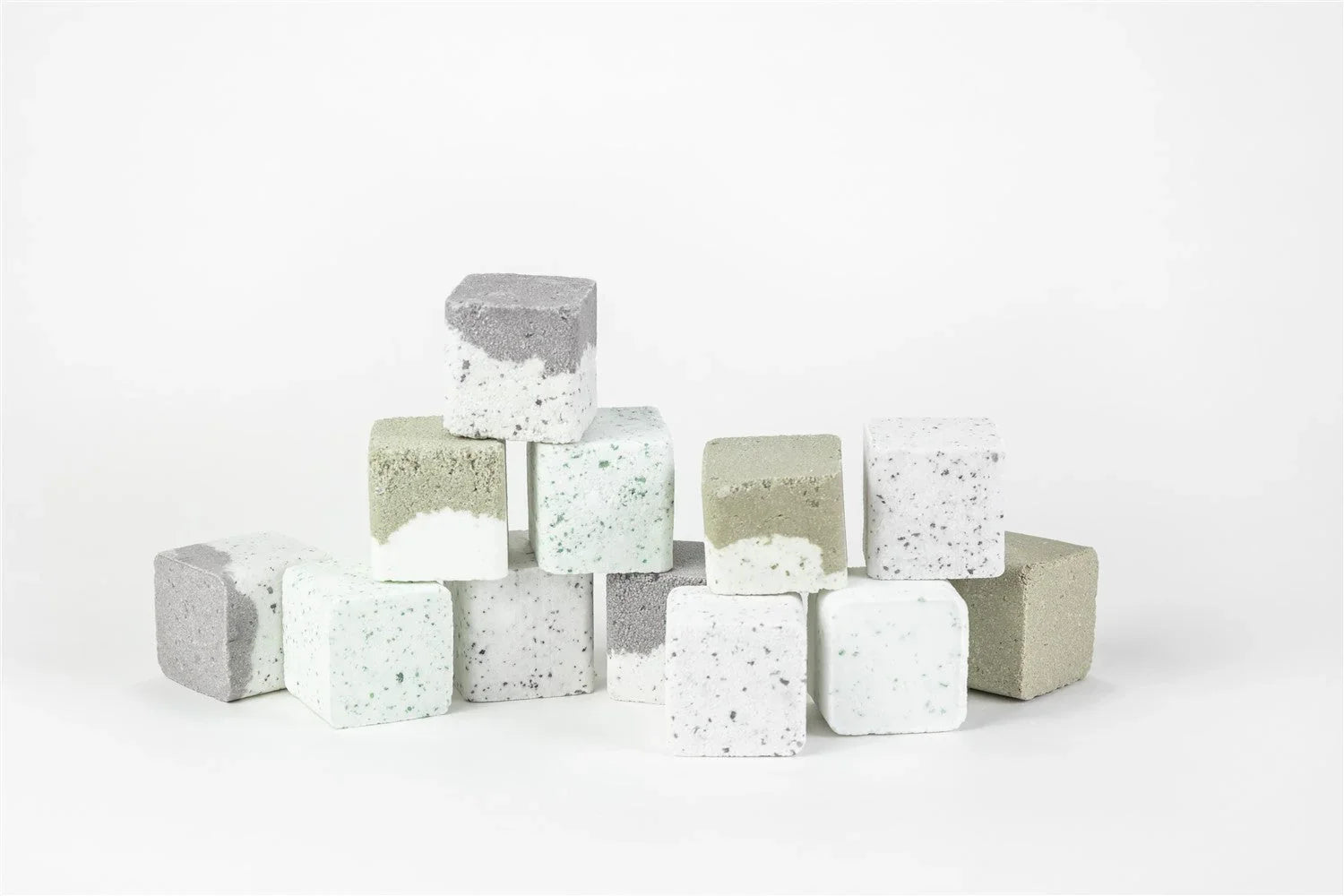 Natural square shower steamers in white, gray, and green, stacked on a white background