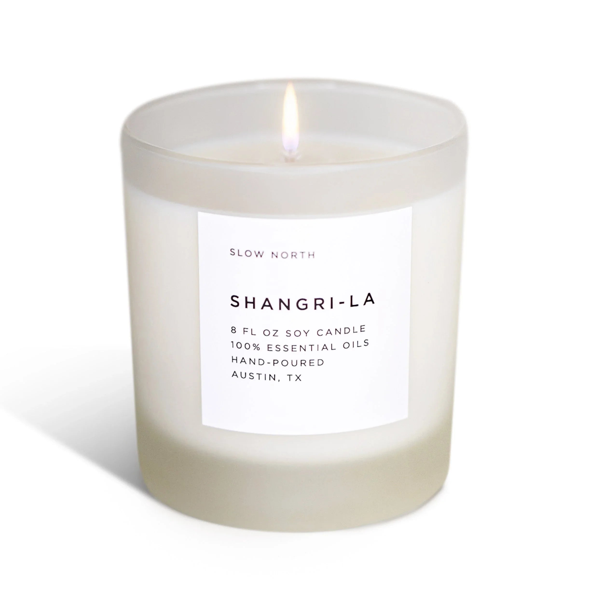 Frosted glass non-toxic soy candle labeled Shangri-La, hand-poured, on white background.