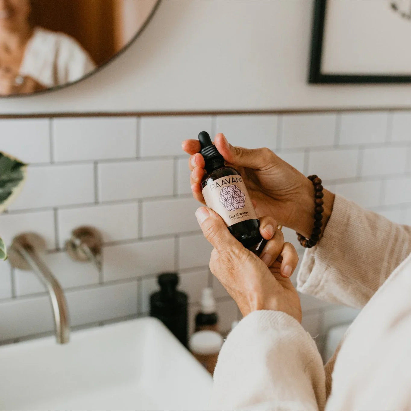 Hands holding Paavani floral water dropper bottle in a modern bathroom, Qu!rk Boutique gift