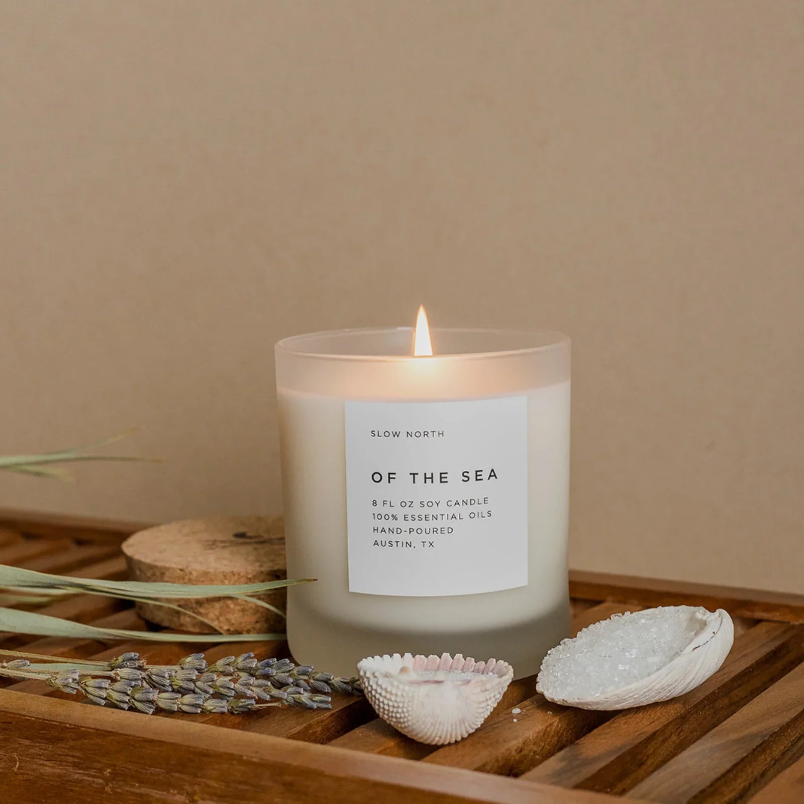Lit Of The Sea soy candle by Slow North on wooden surface with shells and lavender