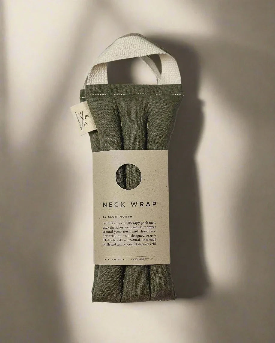 Olive green neck wrap by Slow North with cream handle and informative paper label on white background