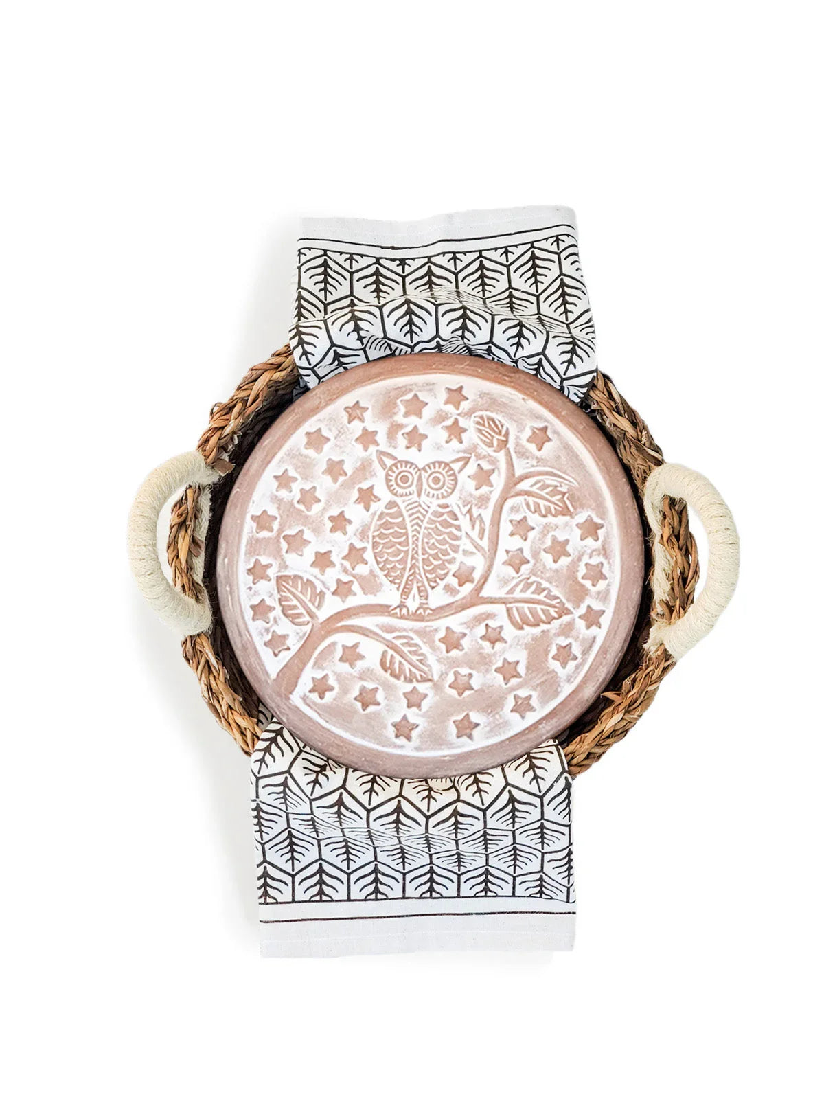 Woven tray with rope handles holding a round owl-patterned ceramic plate on a black and white leaf print cloth