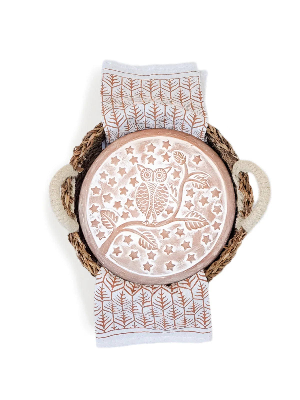 Round ceramic plate with owl and stars design, placed on a patterned cloth inside a woven basket