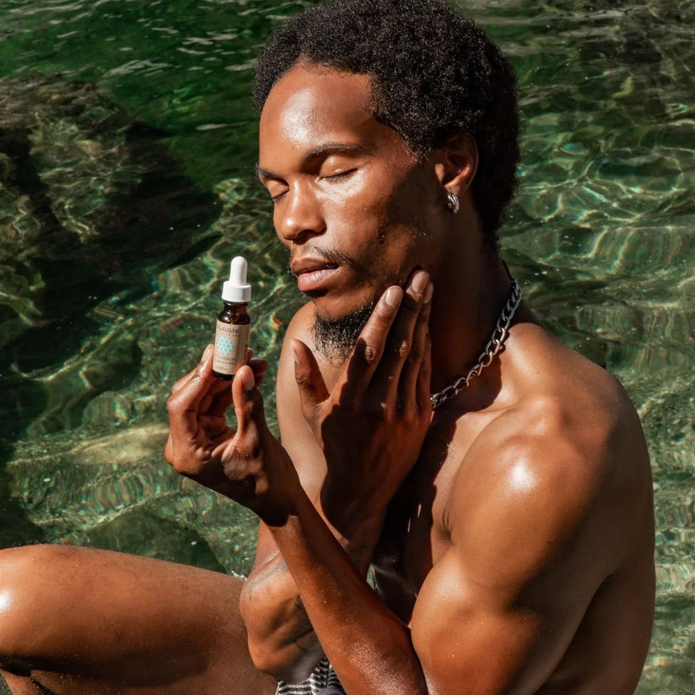 Man applying natural skincare serum by pool, promoting eco-friendly beauty at Qu!rk Boutique
