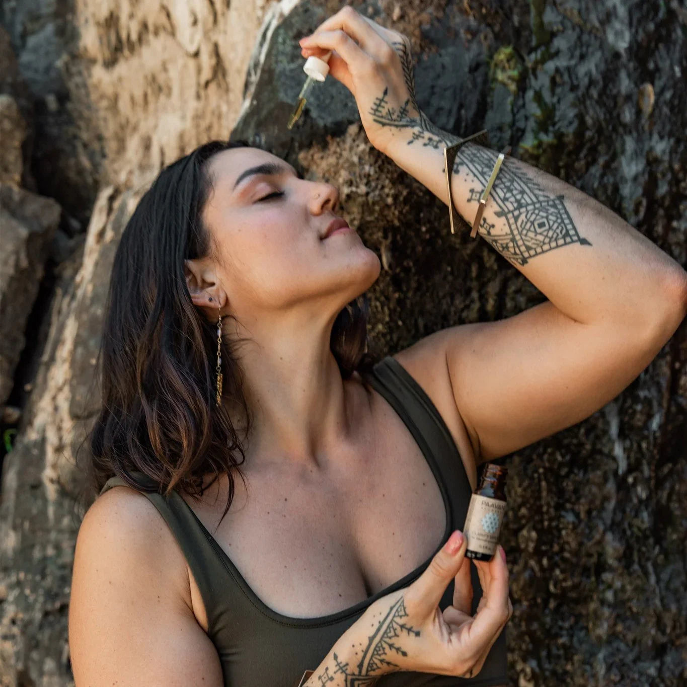 Tattooed woman outdoors applying facial oil, natural skincare at Qu!rk Boutique & Gift Shop