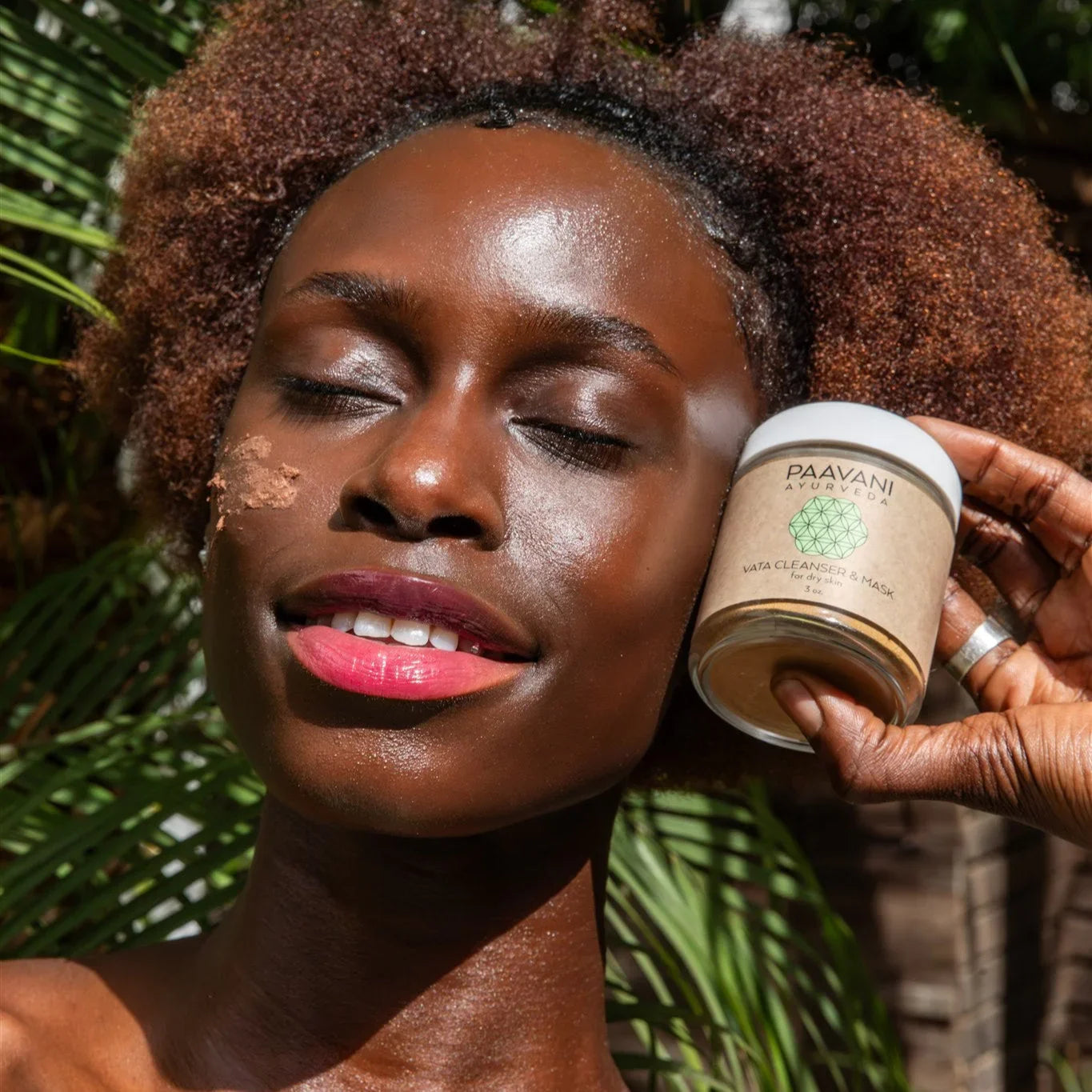 Woman with glowing skin uses PAAVANI Ayurveda Vata Cleanser Mask outdoors, eco skincare product