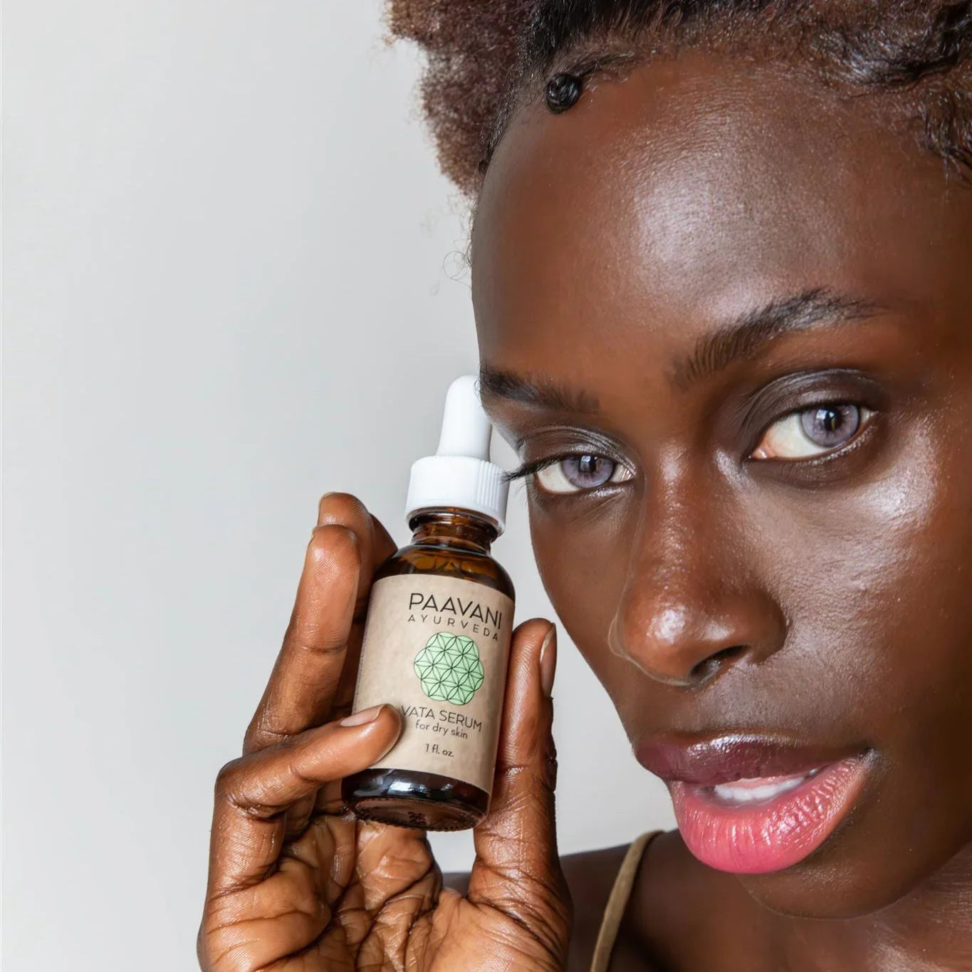 Woman holding Paavani Ayurveda Vata Serum for dry skin near face, promoting natural skincare