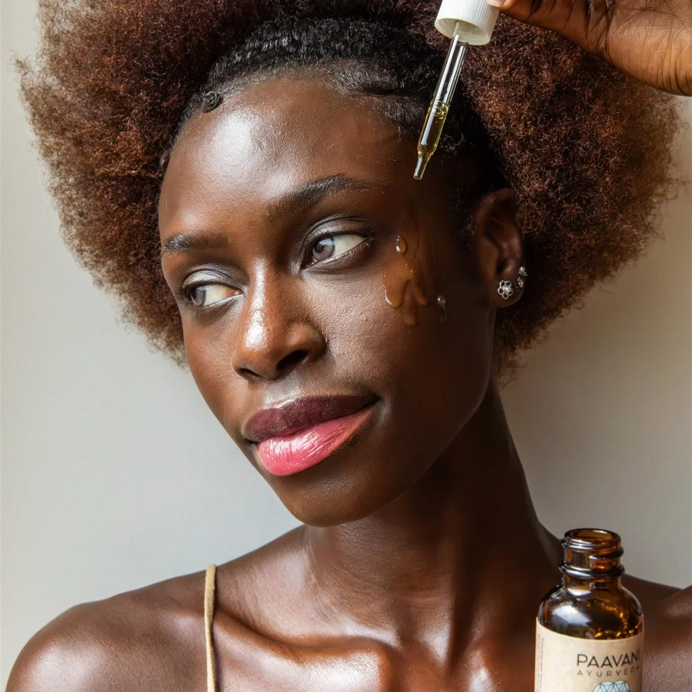 Woman applying Paavani Ayurvedic face oil, showcasing clean beauty at Qu!rk Boutique.