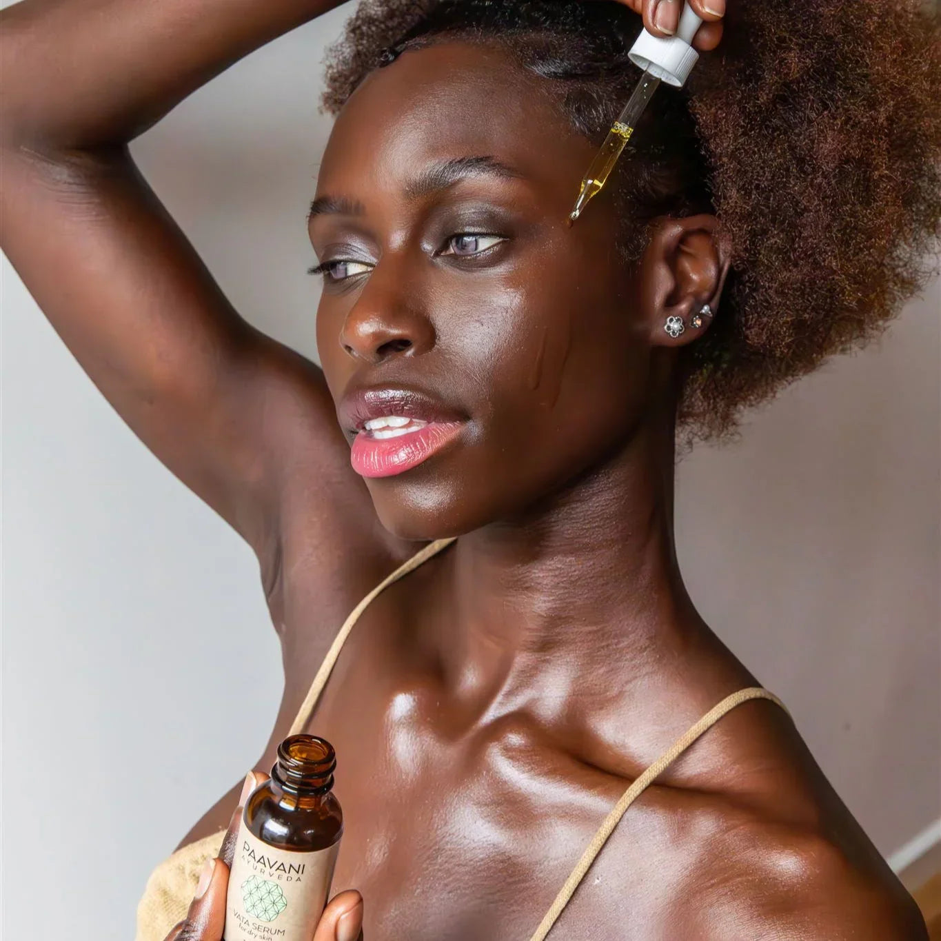 Woman applying Paavani Ayurveda facial serum, showcasing glowing skin and natural beauty, Qu!rk Boutique