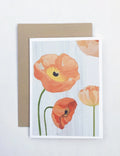Notecard with peach poppy flowers illustration on a light wood background, paired with a kraft paper envelope