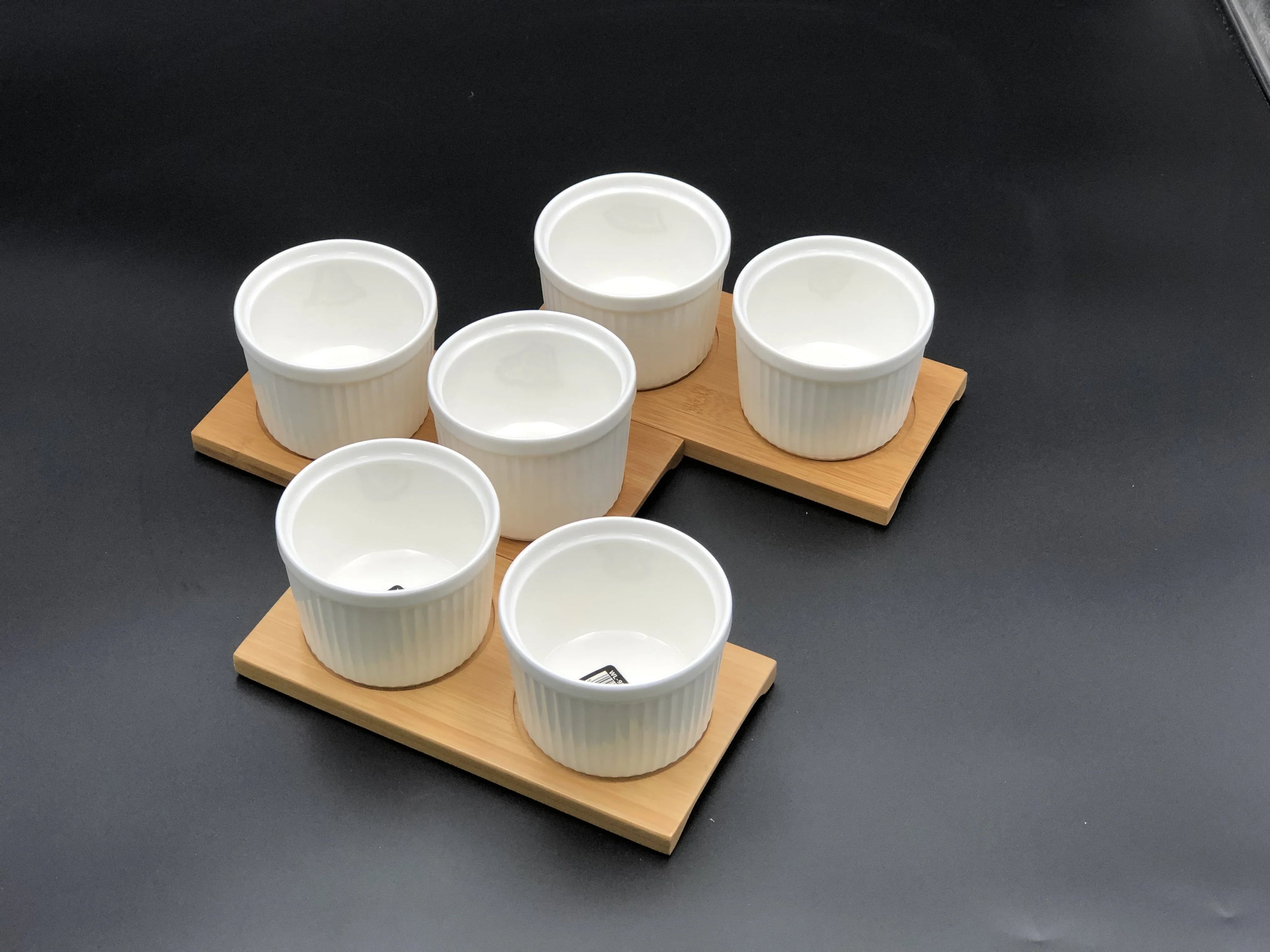 Set of six white ceramic ramekins on bamboo trays, displayed on a black background at Qu!rk Boutique