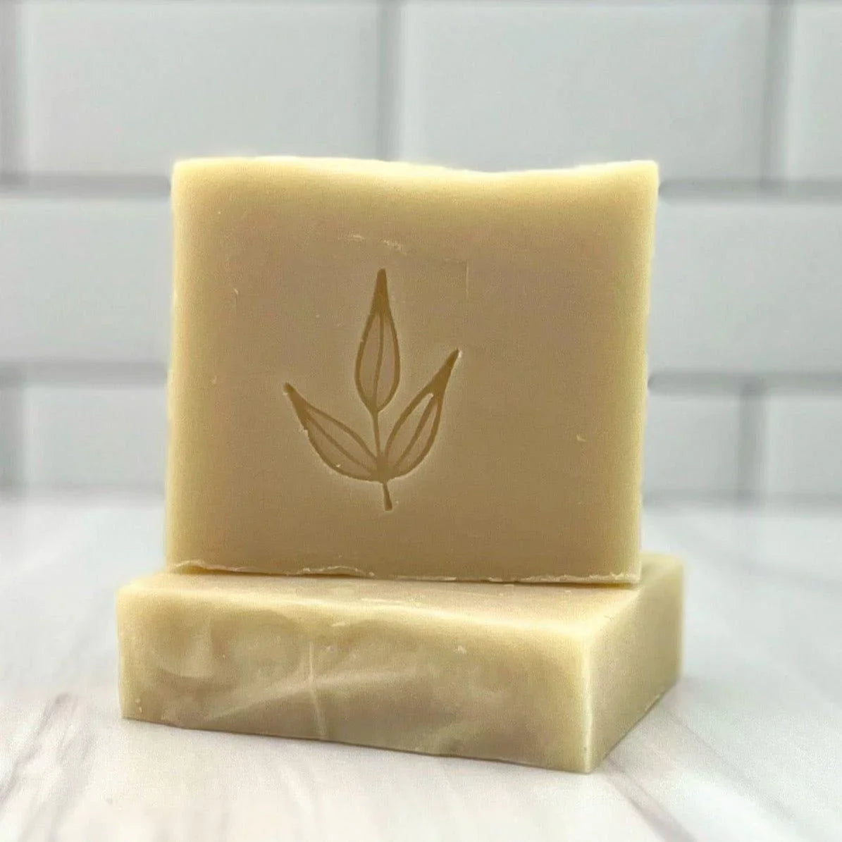 Artisan natural soap bars with leaf imprint, displayed on white tile at Qu!rk Boutique