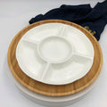 White ceramic divided serving platter on a round bamboo tray with a dark cloth in the background