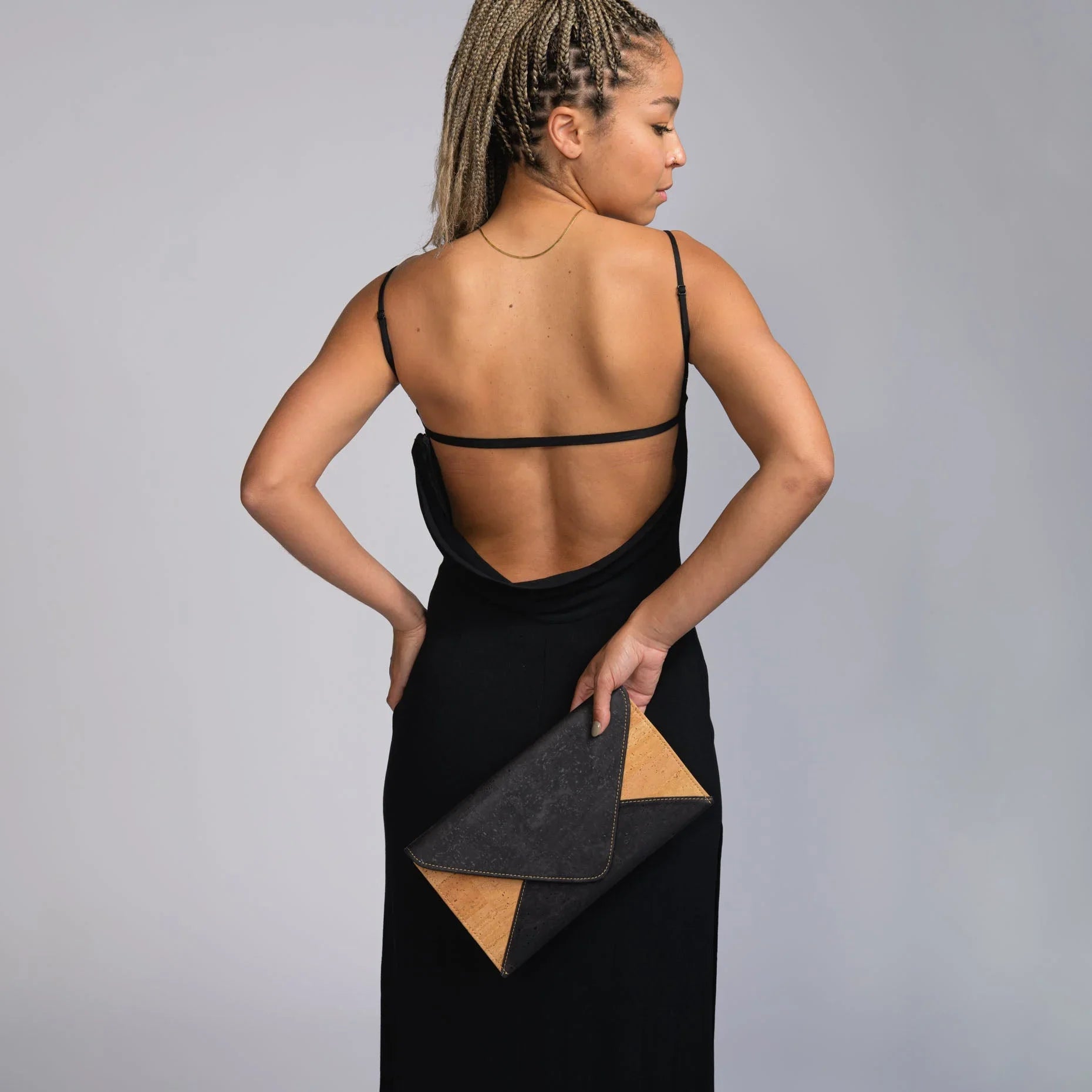 Woman in black backless dress holding eco-friendly clutch, Qu!rk Boutique fashion