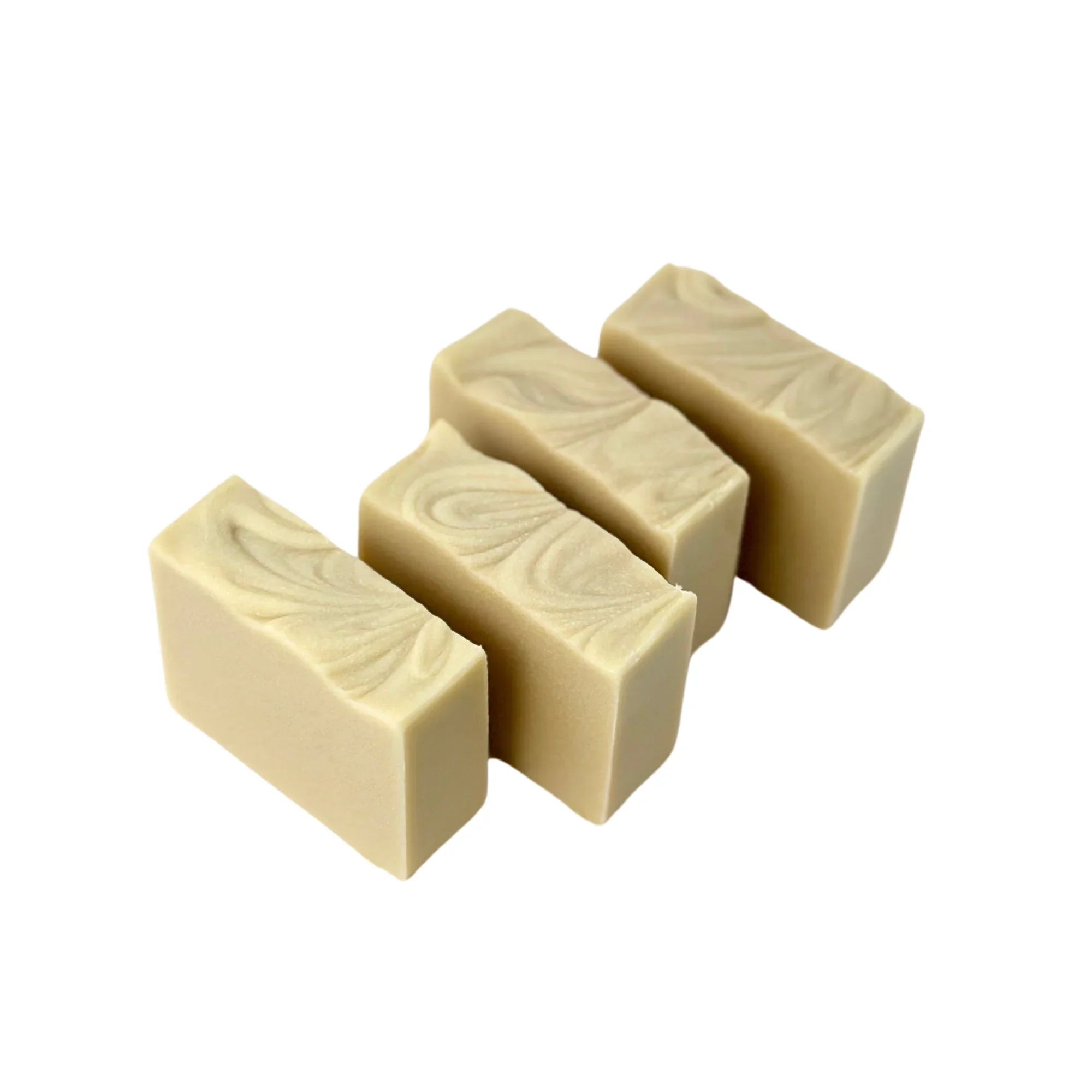 Four rectangular beige artisan soap bars with smooth swirled tops on white background