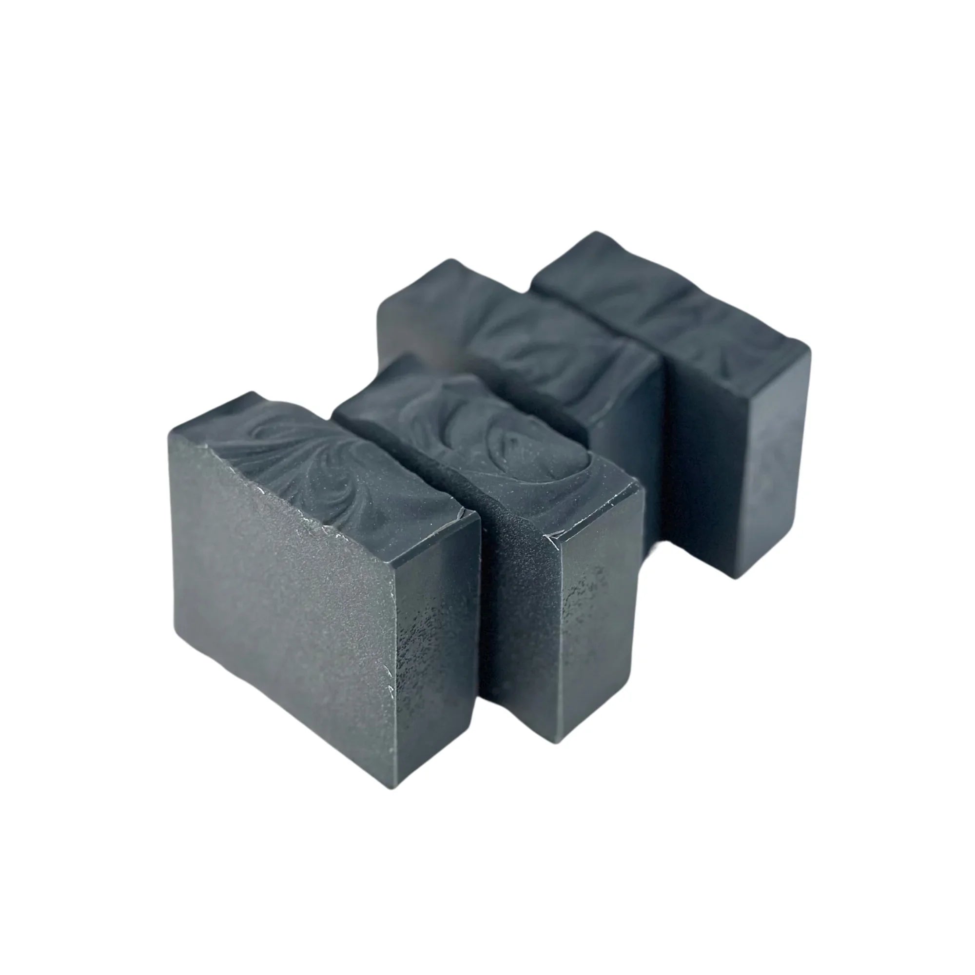 Four rectangular black charcoal soap bars with textured tops on white background