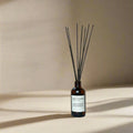 Forest Bathing reed diffuser in amber glass bottle with black sticks on neutral background
