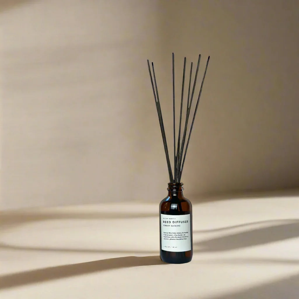 Forest Bathing reed diffuser in amber glass bottle with black sticks on neutral background