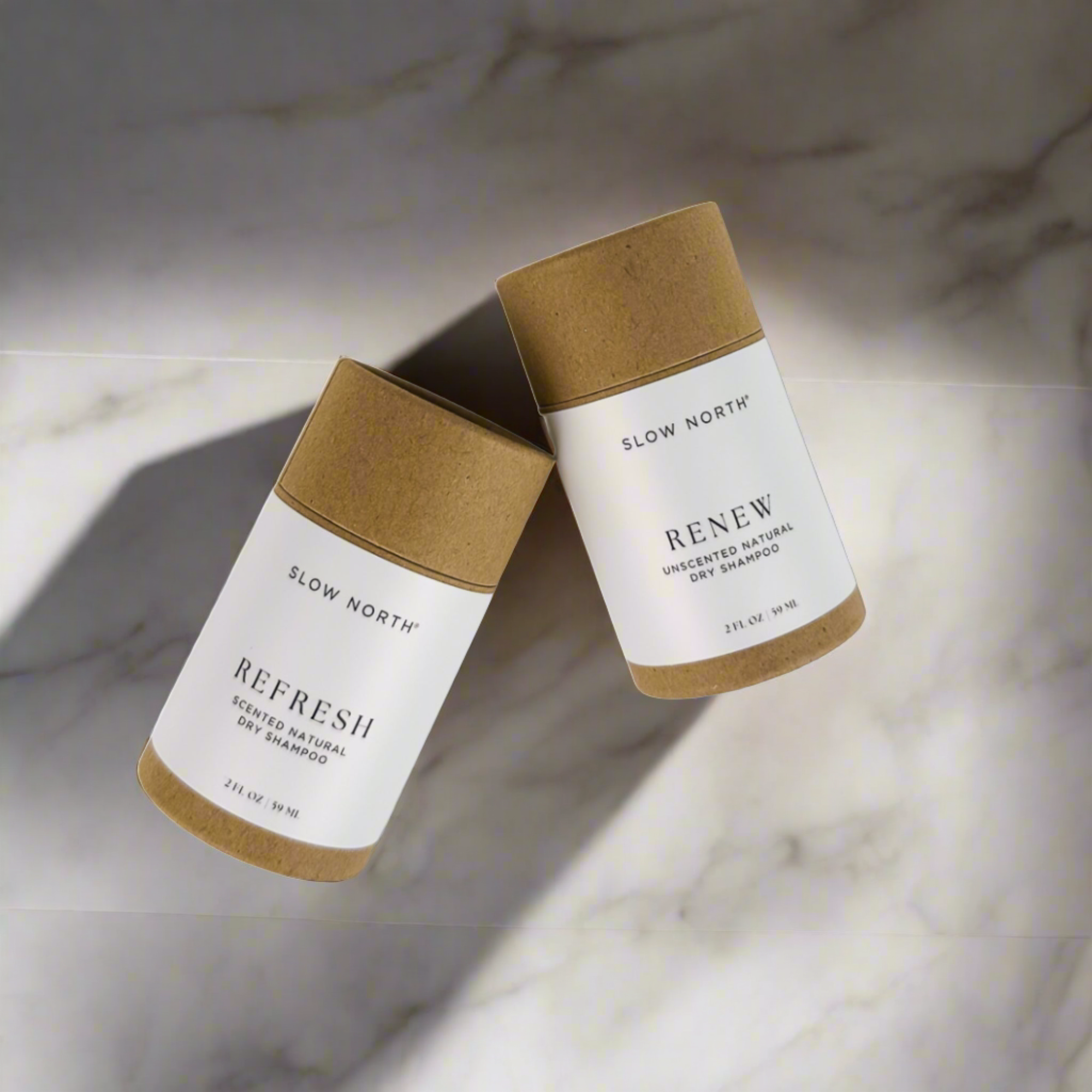 Slow North natural dry shampoo containers labeled Refresh and Renew on marble surface