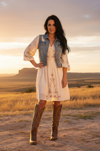 Brown cowboy boot with intricate white embroidery on a white background