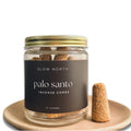 Slow North palo santo incense cones in glass jar with gold lid, displayed on a ceramic plate.