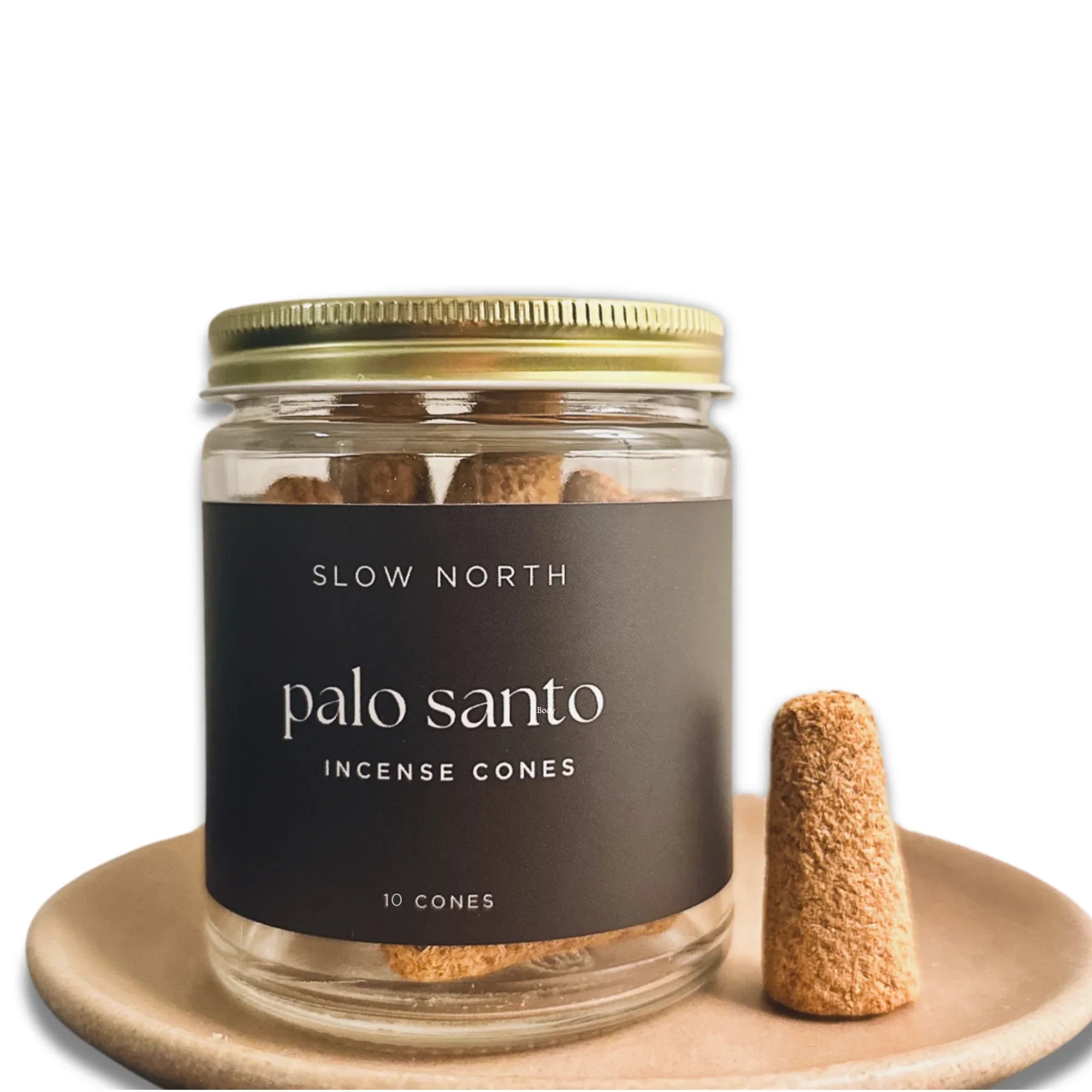 Slow North palo santo incense cones in glass jar with gold lid, displayed on a ceramic plate.