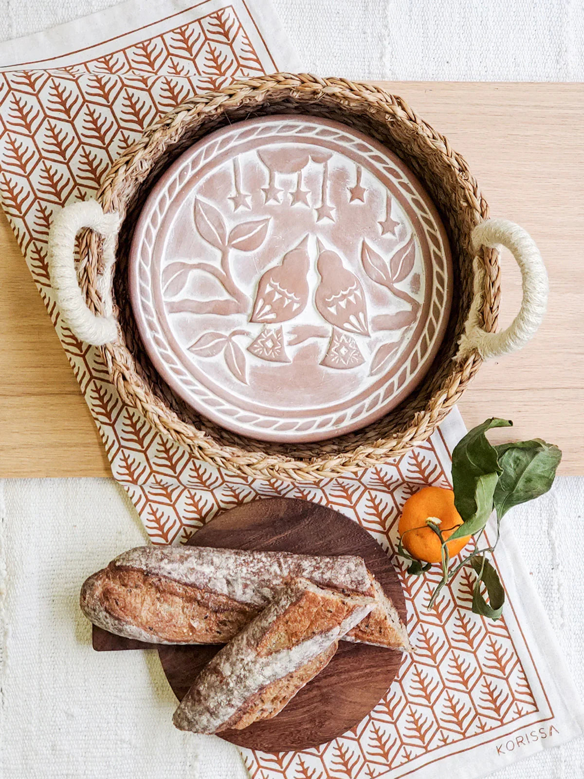 Artist-designed round bread warmer basket with lovebird motif, rustic baguettes, and orange, Qu!rk Boutique