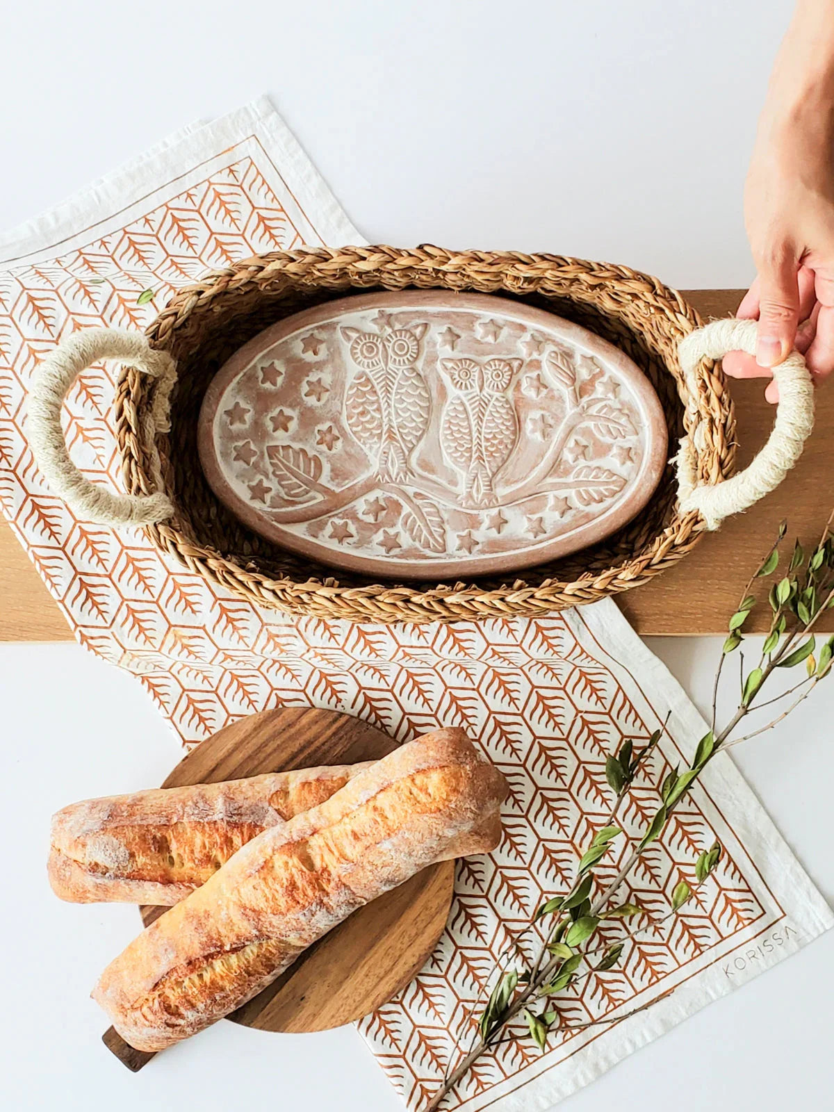 Oval woven bread warmer basket with owl pattern ceramic insert, hand holding basket handle