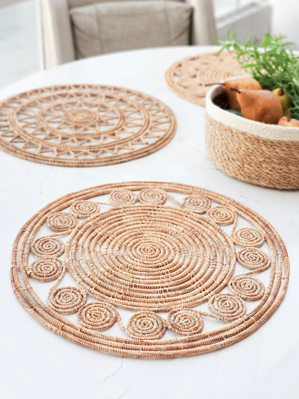 Natural woven palm fiber placemats with intricate circular patterns on white table