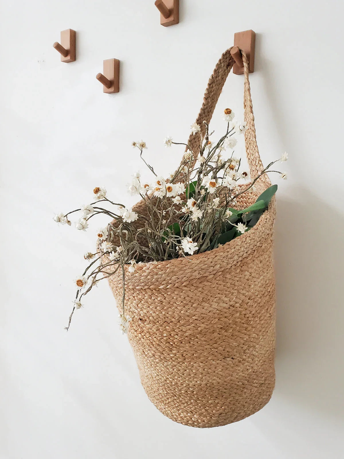 Woven hanging basket with dried white daisies on wall hooks, Qu!rk Boutique home decor