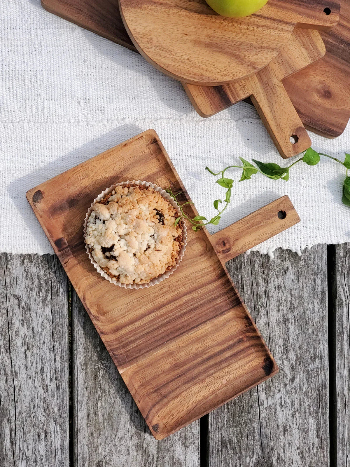 Rectangular wooden serving tray with crumb pastry on white cloth and rustic wooden surface