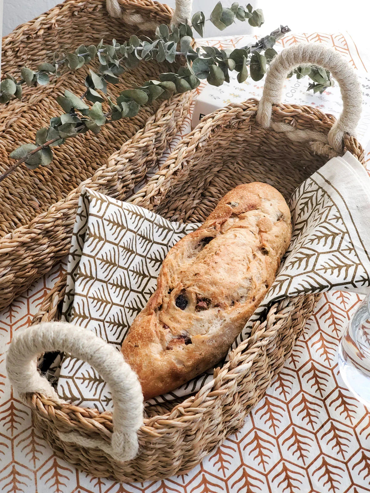 Savar bread basket set of 2 with white rope handles, one holding patterned napkin and rustic bread loaf