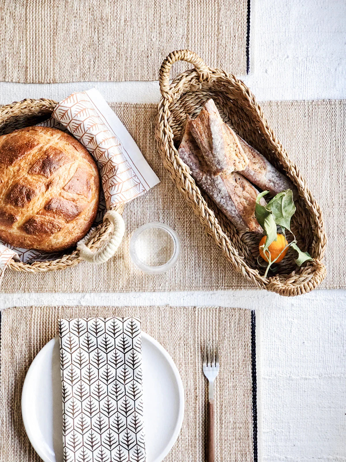 Woven bread baskets with natural handles holding artisan bread and baguettes on rustic placemats