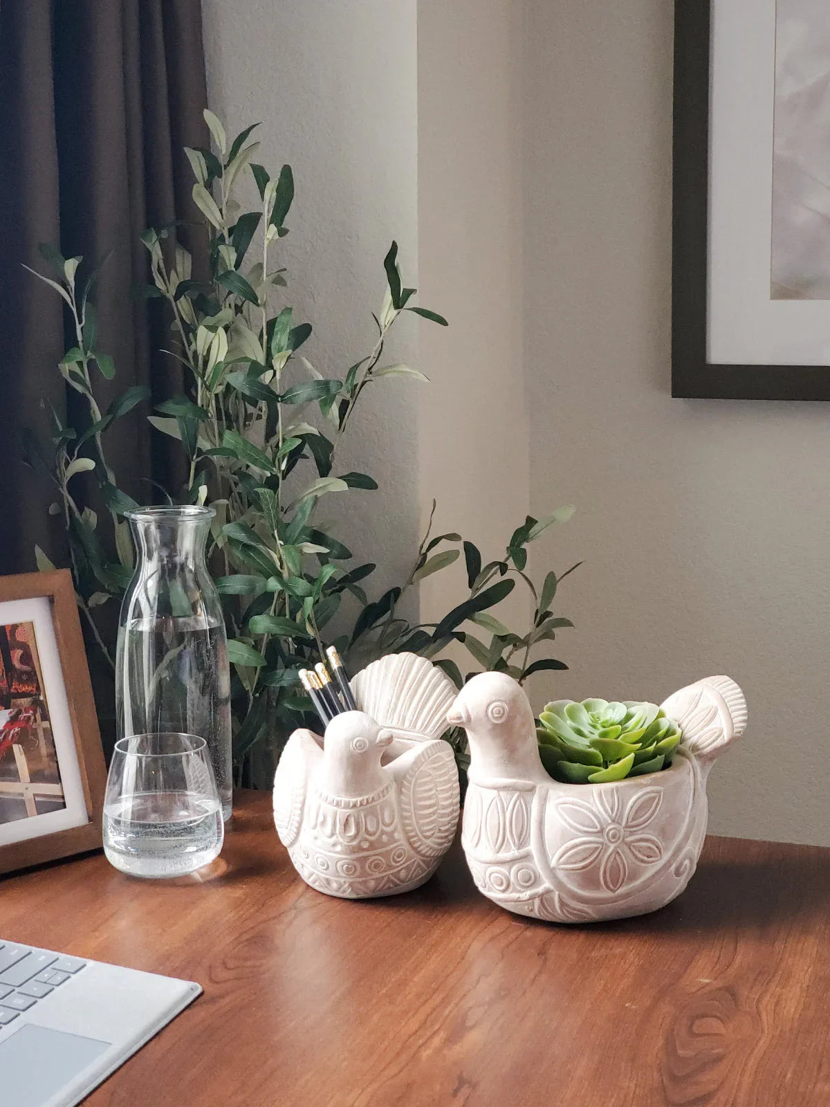 Terracotta bird-shaped planter with green succulent and matching bird-shaped pencil holder on wooden desk