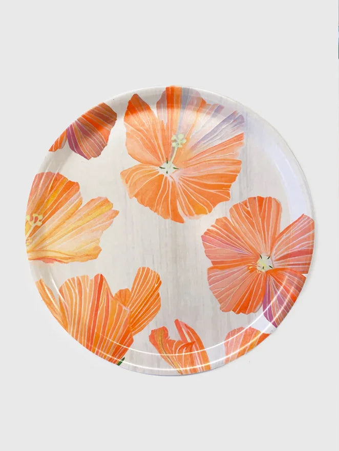 Round serving tray with vibrant orange hibiscus flowers on a light wood-textured background