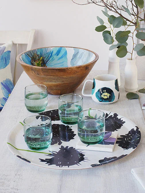 Winter tablescape with wooden bowl, floral tray holding four glasses, and matching floral mug on white table