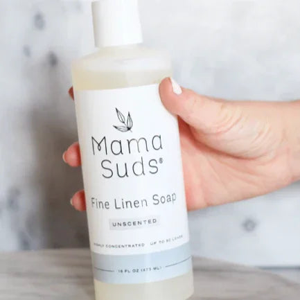 Hand holding Mama Suds Fine Linen Soap bottle, eco-friendly laundry product at Qu!rk Boutique