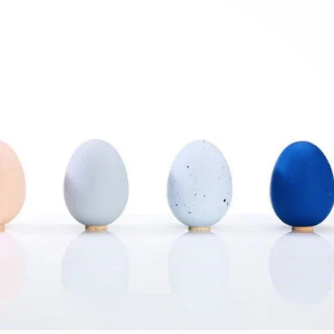 Four pastel and blue egg-shaped decorative objects on a white surface, Qu!rk Boutique style.