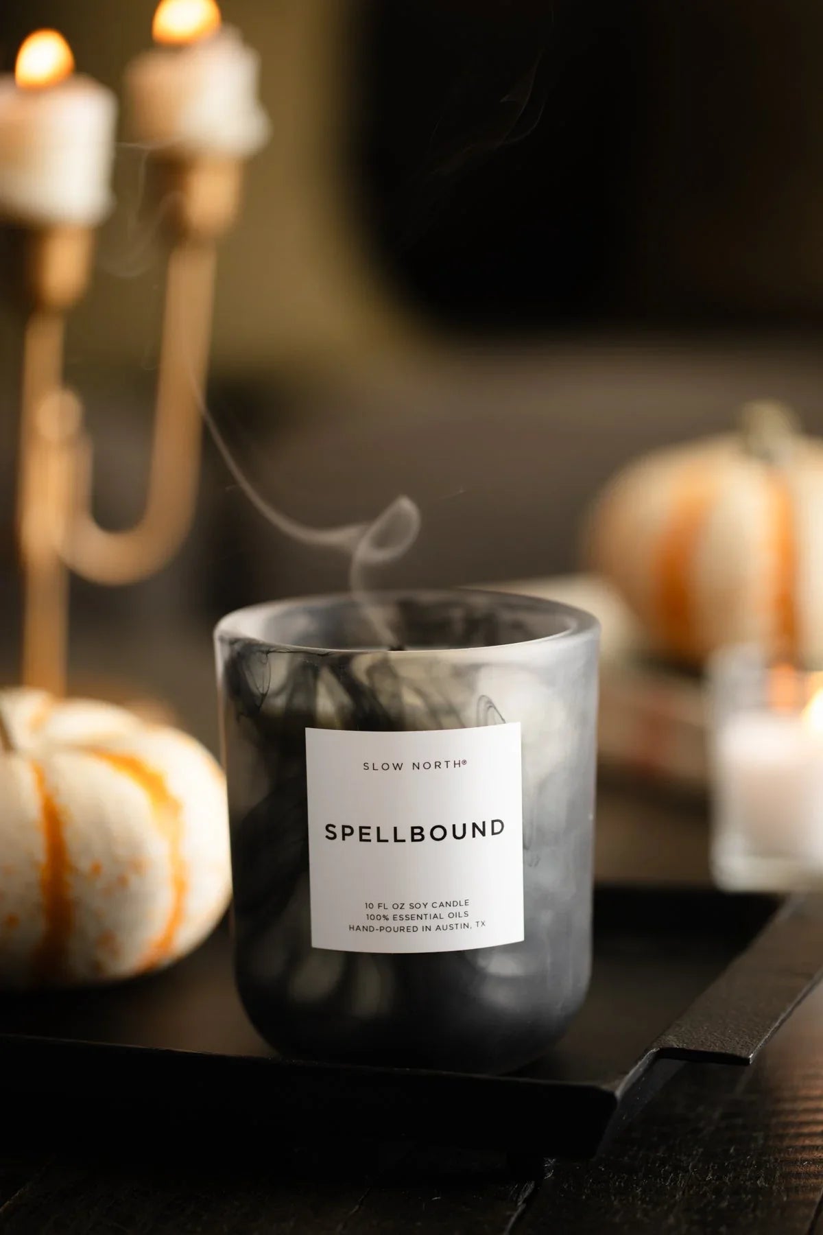 Slow North Spellbound soy candle with smoke on black tray, fall decor with mini pumpkins and candles