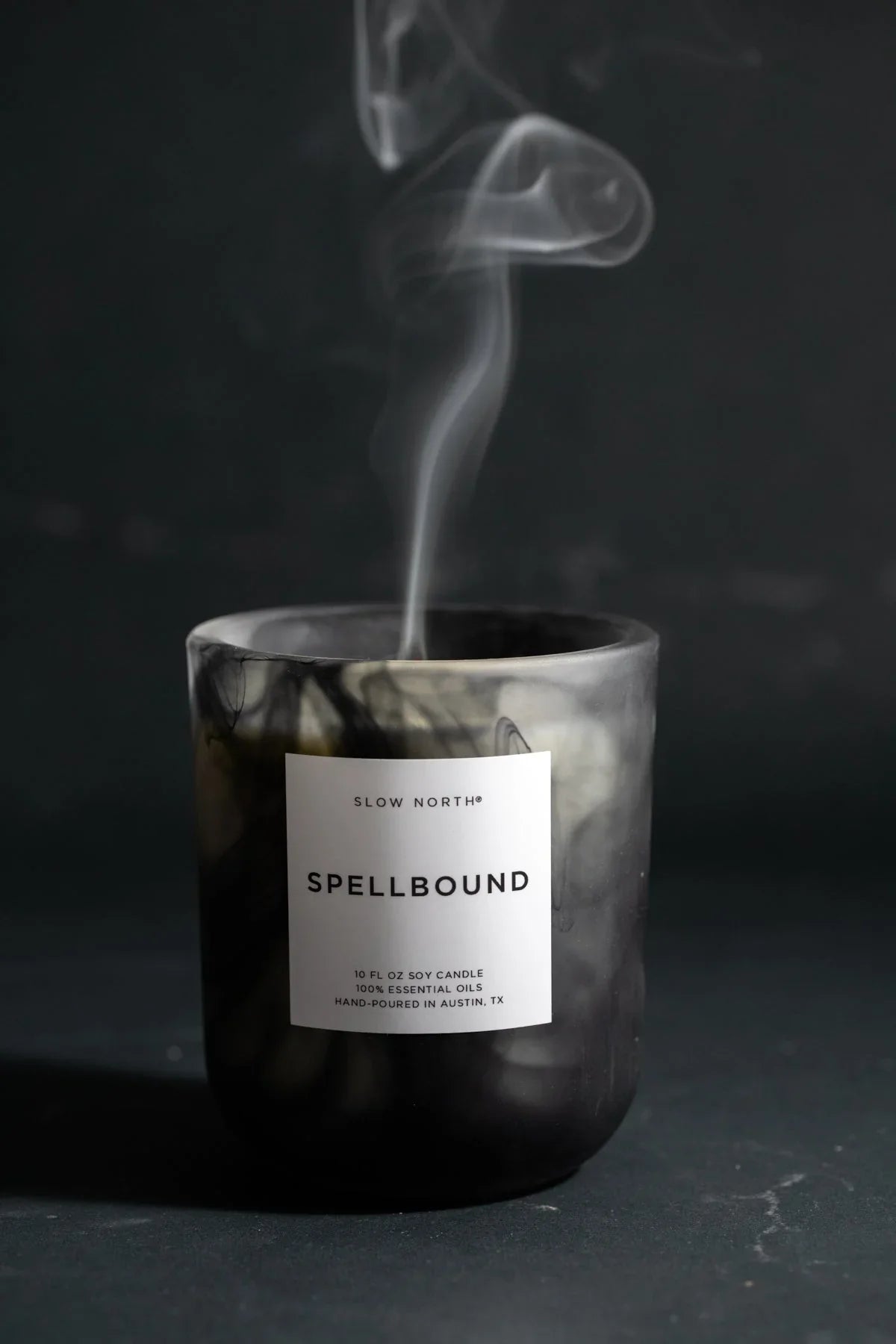 Black Spellbound soy candle by Slow North with smoke rising on dark background