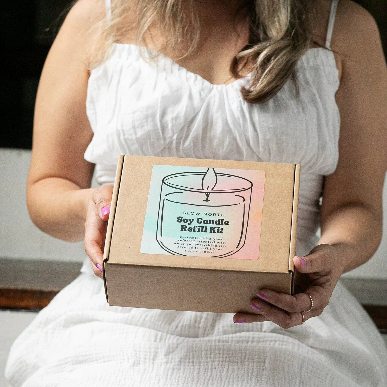 Woman in white dress holding a Slow North soy candle refill kit, Qu!rk Boutique eco-friendly gift