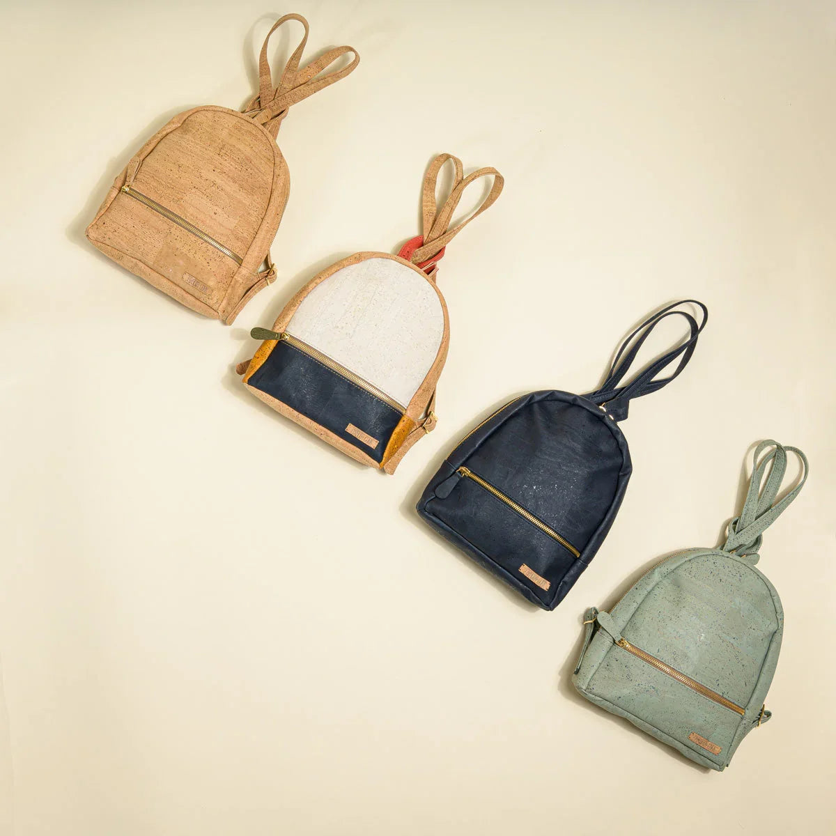 Four eco-friendly cork backpacks in neutral and pastel colors on a light background, Qu!rk Boutique