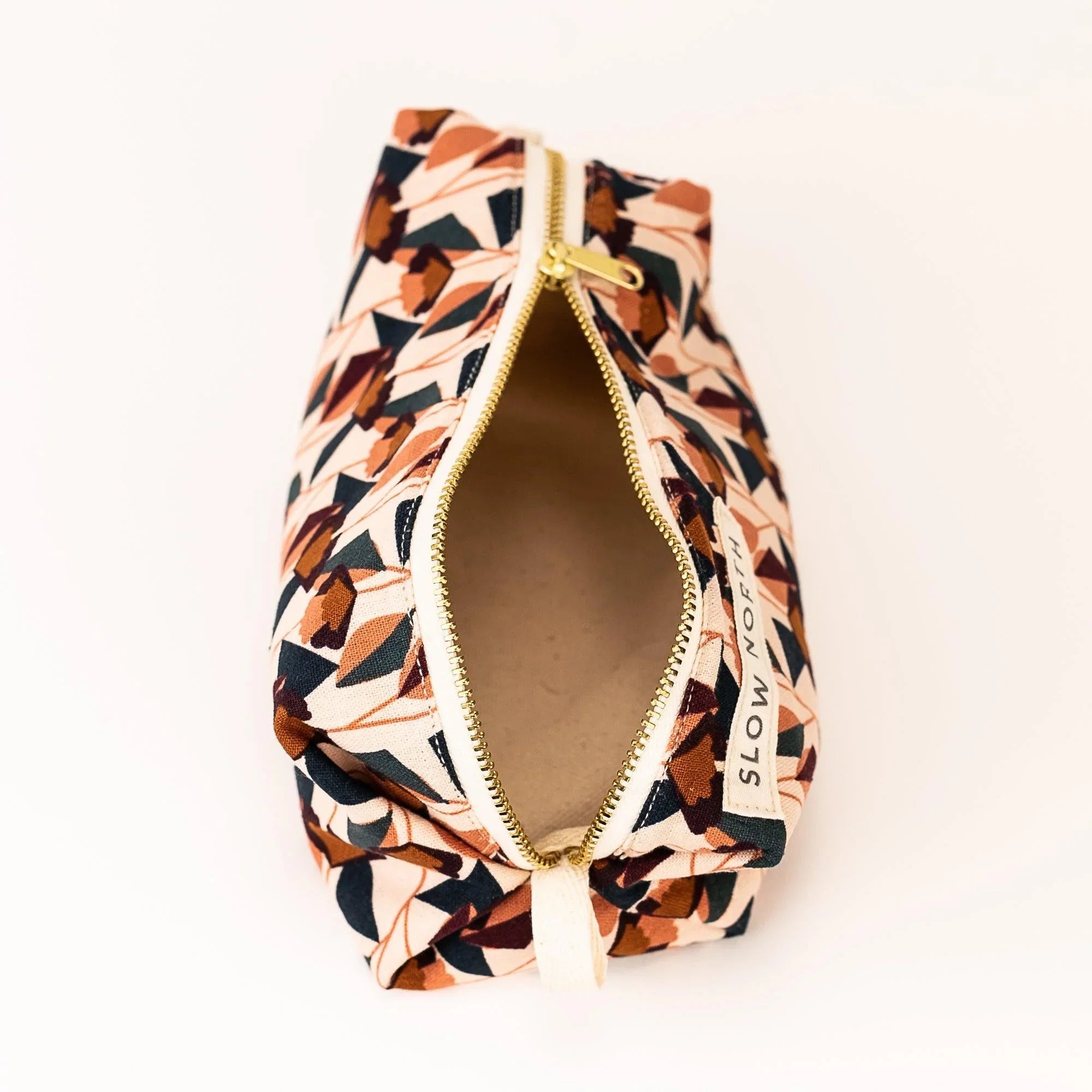 Open blush floral travel pouch with gold zipper and Slow North label on white background