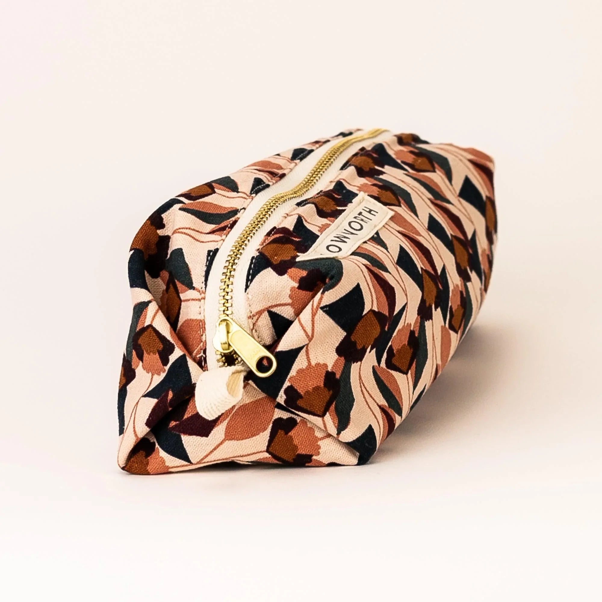 Blush floral travel pouch with gold zipper and OWLOTH label on white background