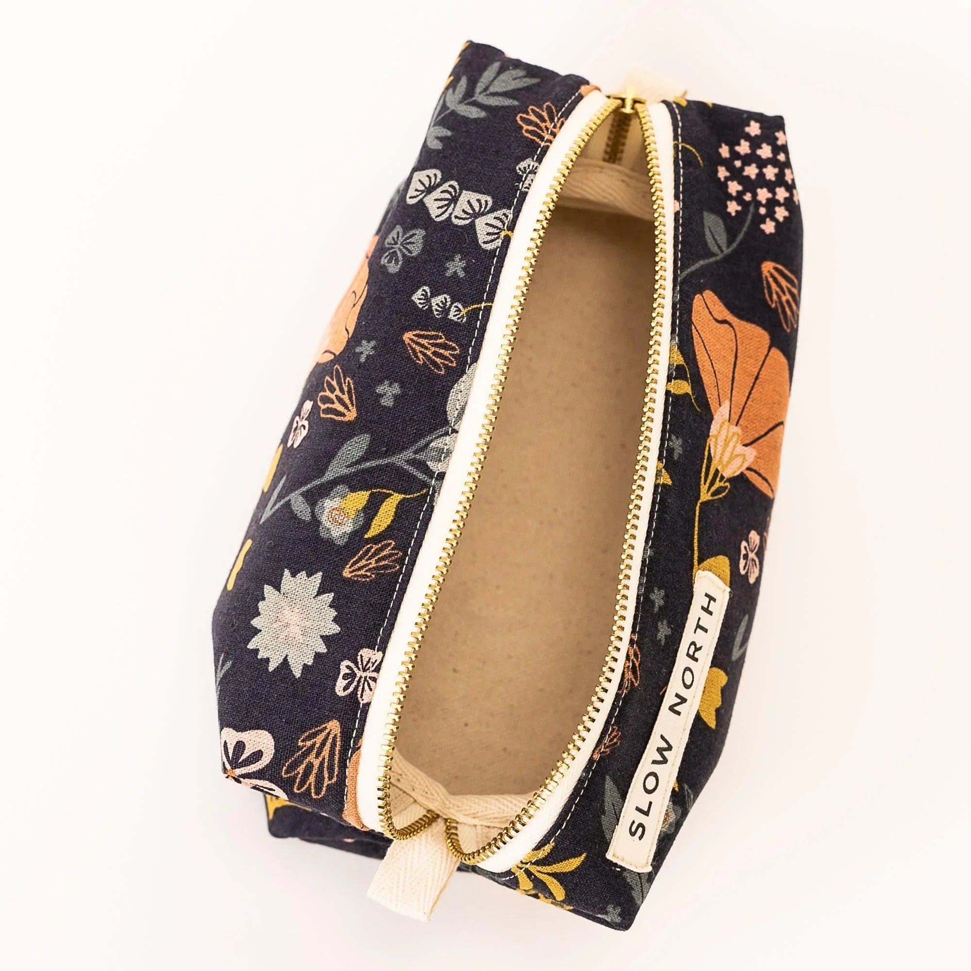 Open floral printed travel pouch with gold zipper and Slow North label on white background