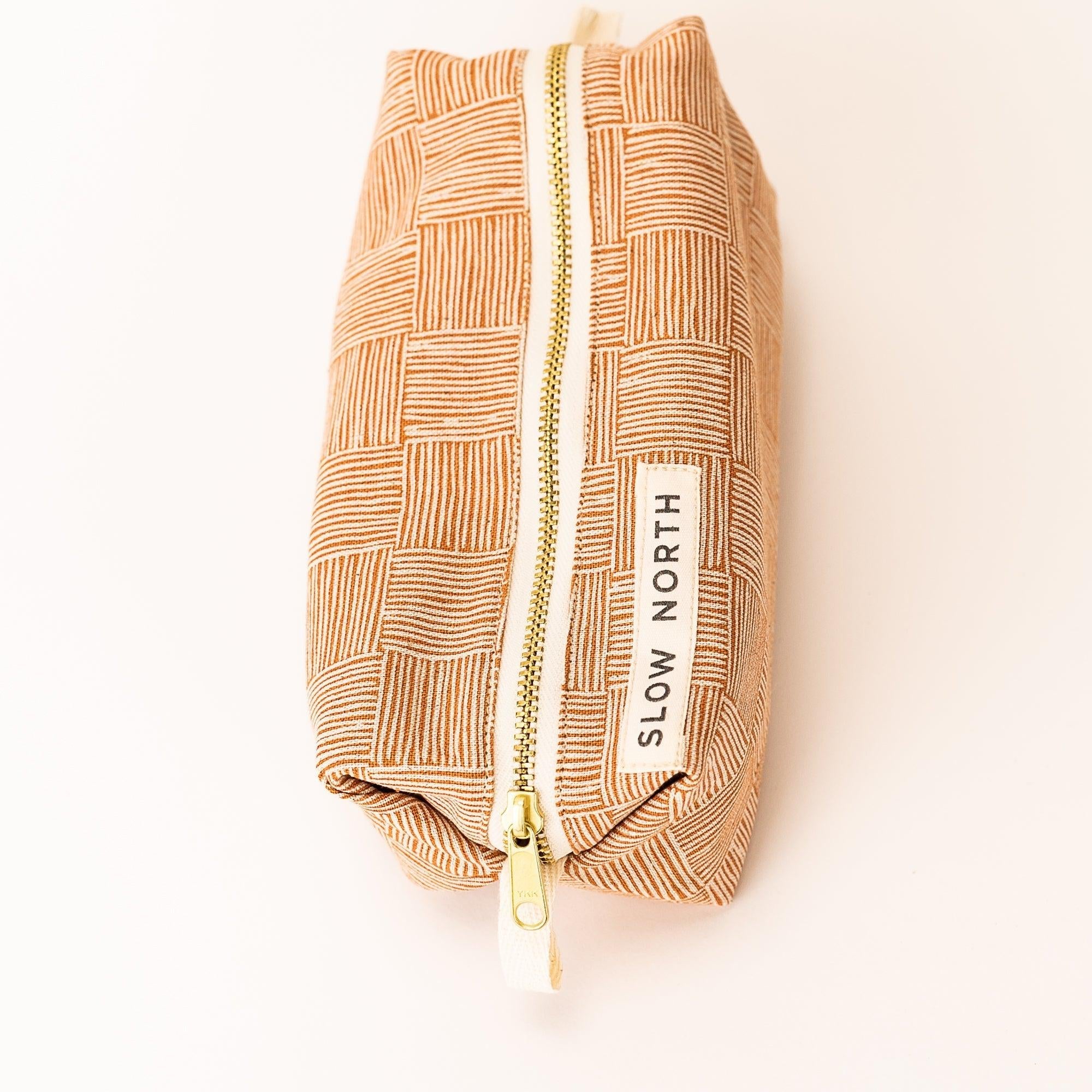 Copper patterned travel pouch with gold zipper and Slow North label on white background