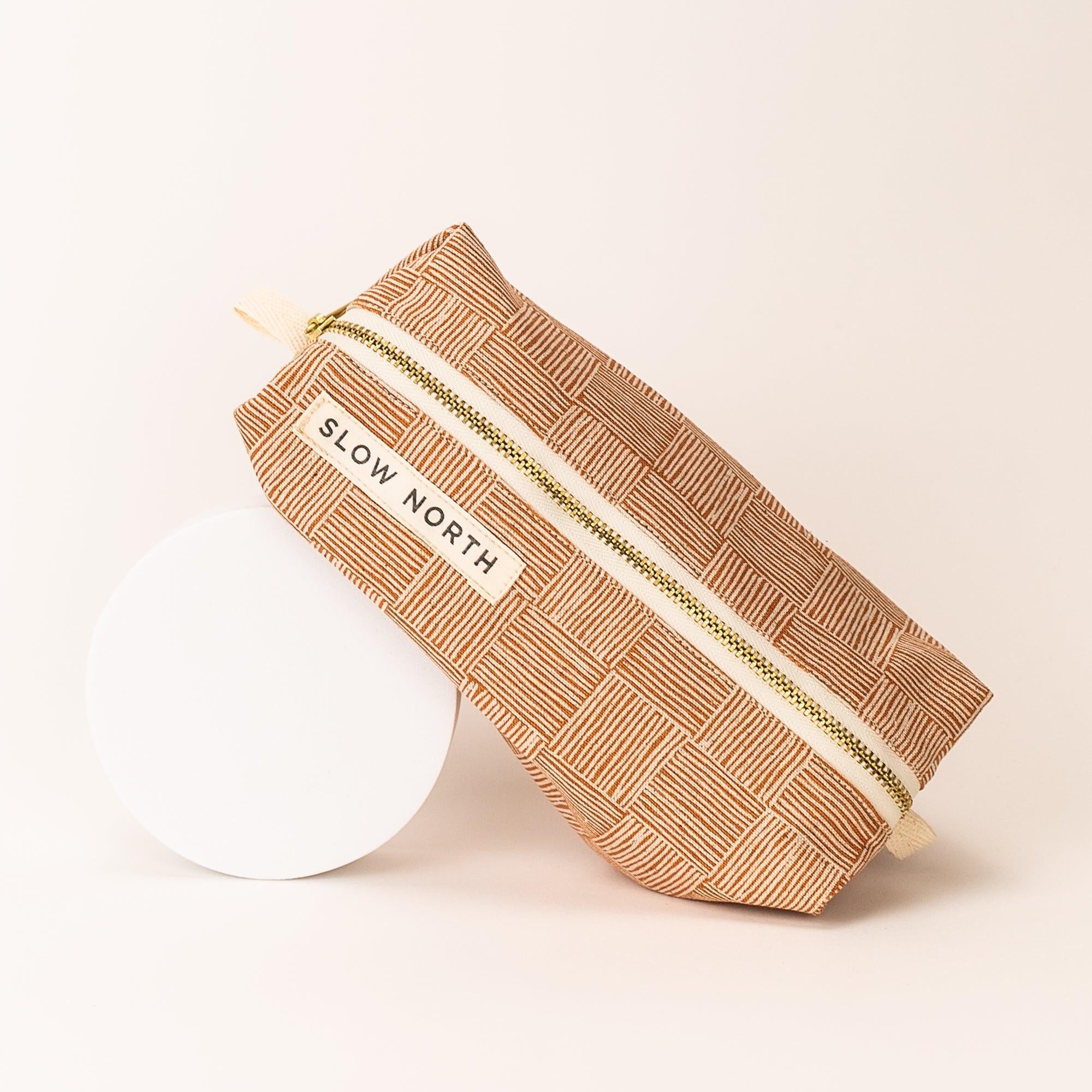 Copper Fields travel pouch with geometric striped pattern and gold zipper, labeled Slow North