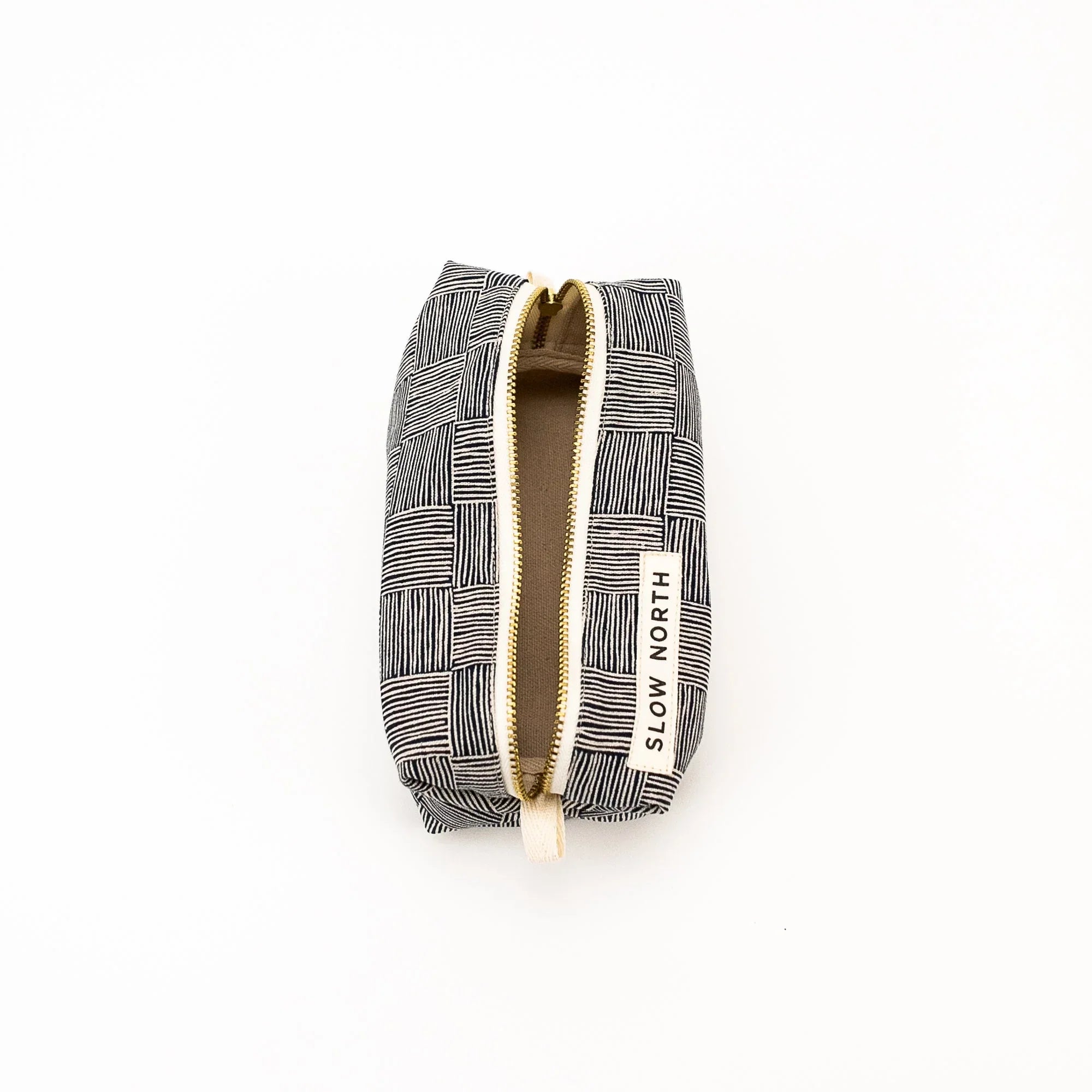 Black and white patterned travel pouch with gold zipper and Slow North label on white background