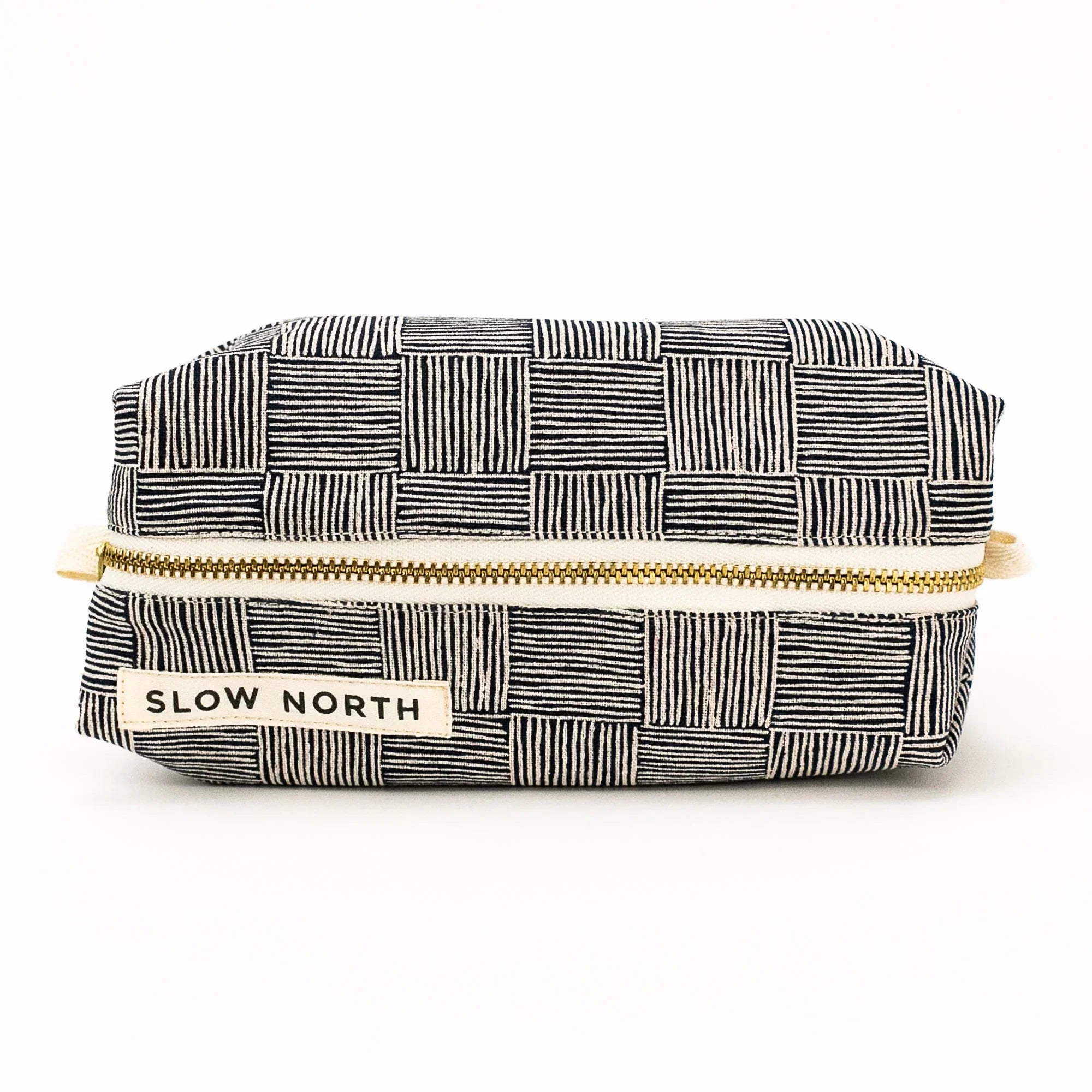 Black and white checkered travel pouch with gold zipper and Slow North label